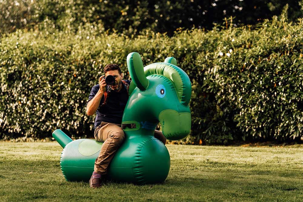 Somerset wedding photographer Paul Aston sat on an inflatable animal taking a fun photograph with his camera.