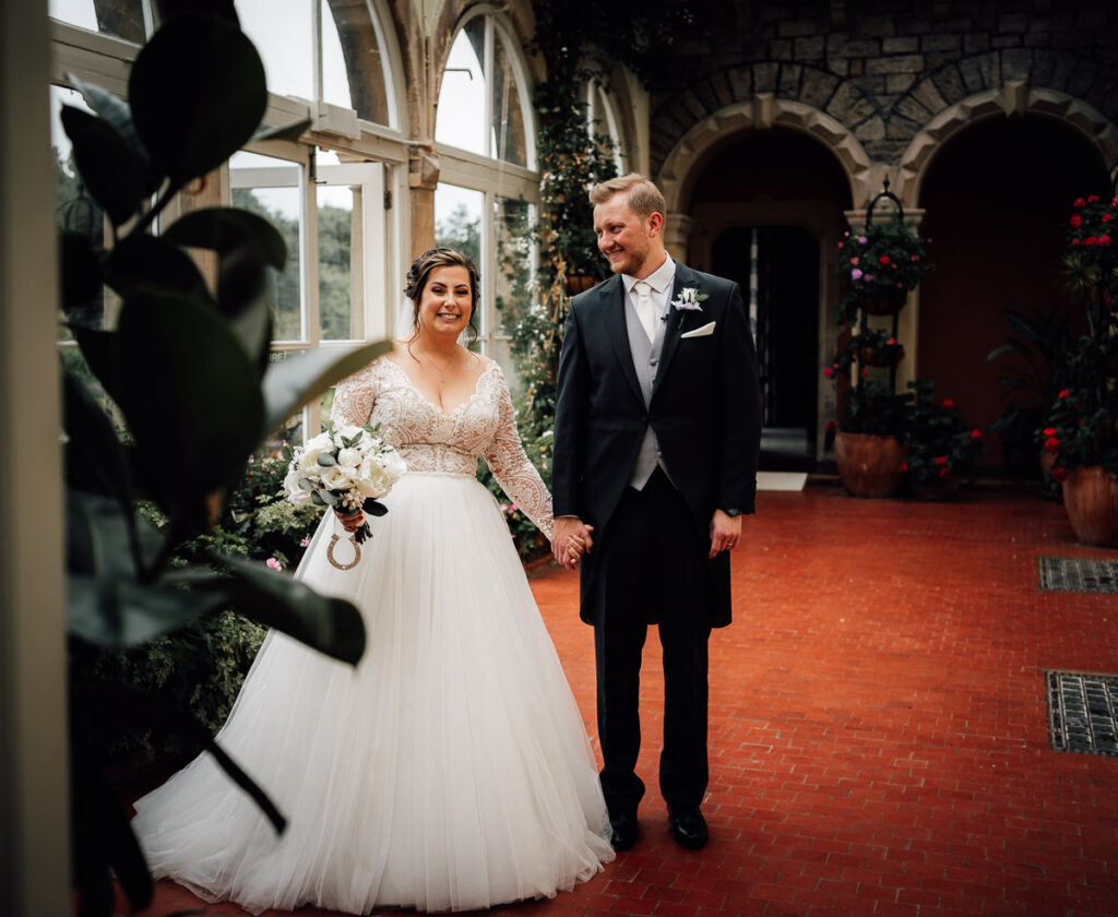Bride and groom standing in the conservatory at clevedon hall