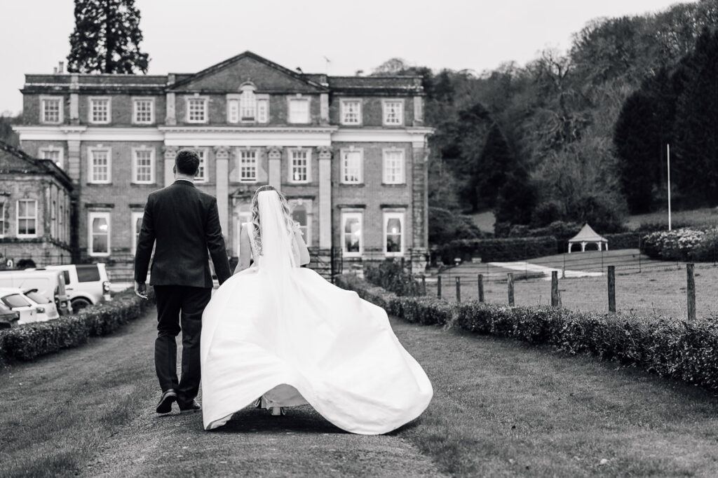Black and White wedding Photography of bride and groom walking driveway