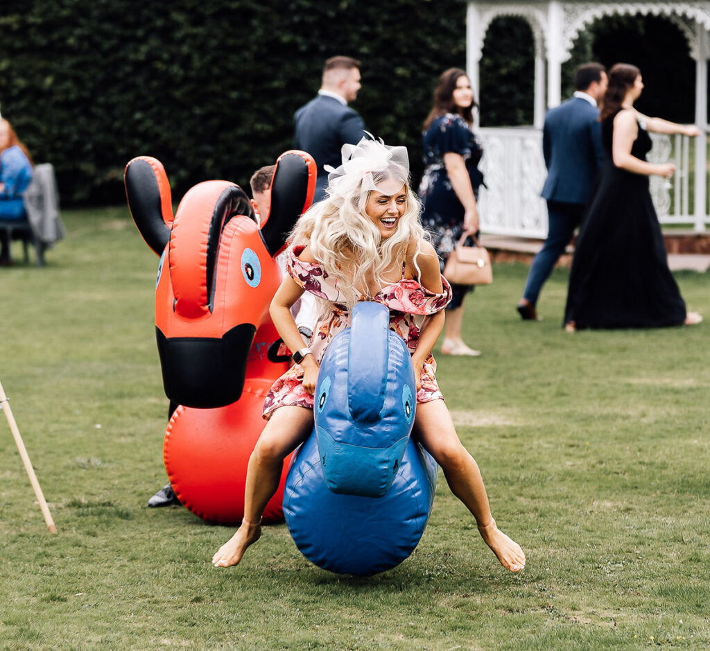woman on an inflatable animal, bouncing around a little drunk at crowcombe court. Wedding Photography Somerset Paul Aston Photography