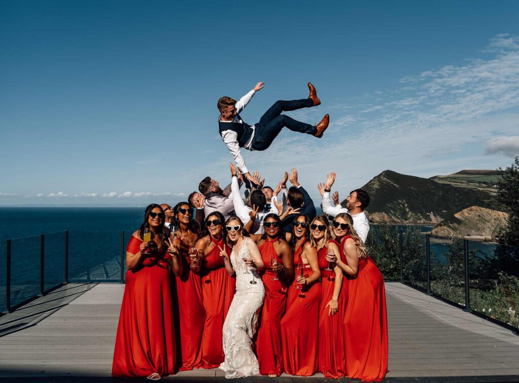 Groom is tossed into the air by the groomsman and the bride and bridesmaids celebrate, amazing award winning photography