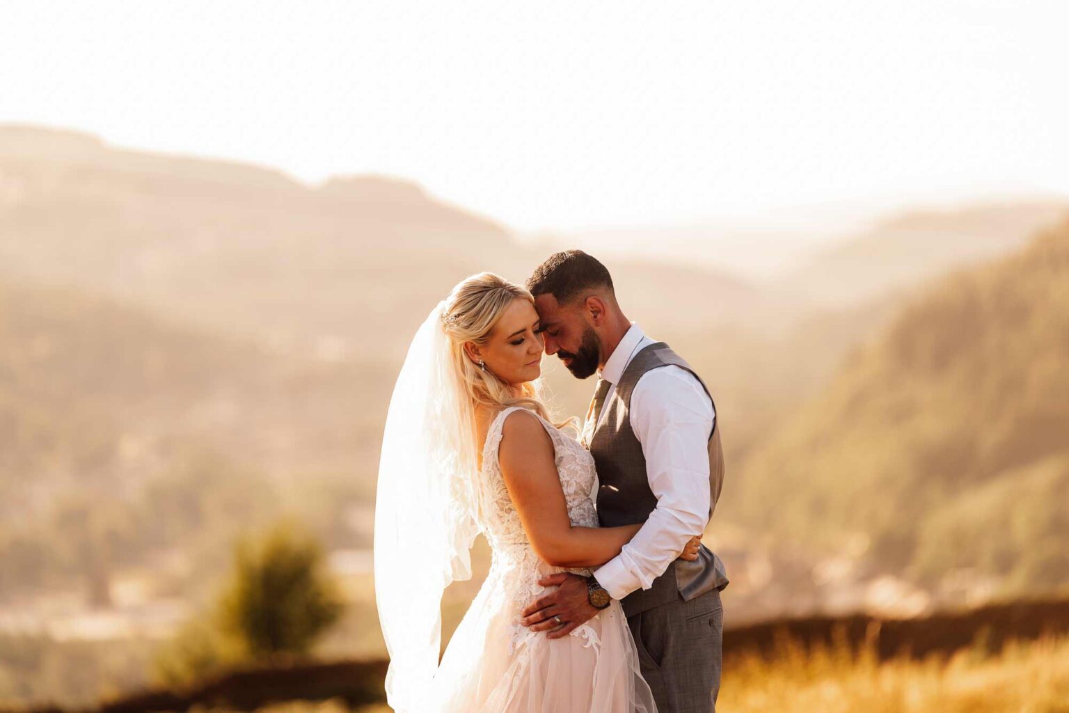 Young married couple embrace in front of stunning backdrop of valley