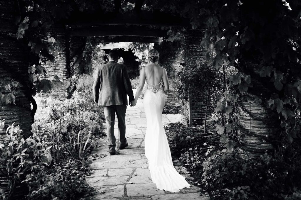 Bride and groom walking through the gardens of hestercombe gardens on their wedding day.