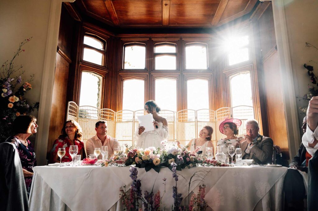 Bride standing at the top table with her bride sat next to her while she gives her speech. wedding was at St Audries park