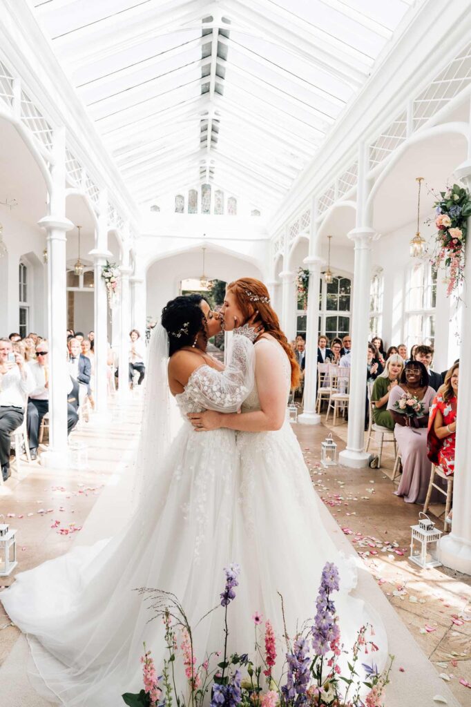 Wedding Photography Somerset Bride and Bride having their first kiss during ceremony at st audries in the the orangery ceremony building