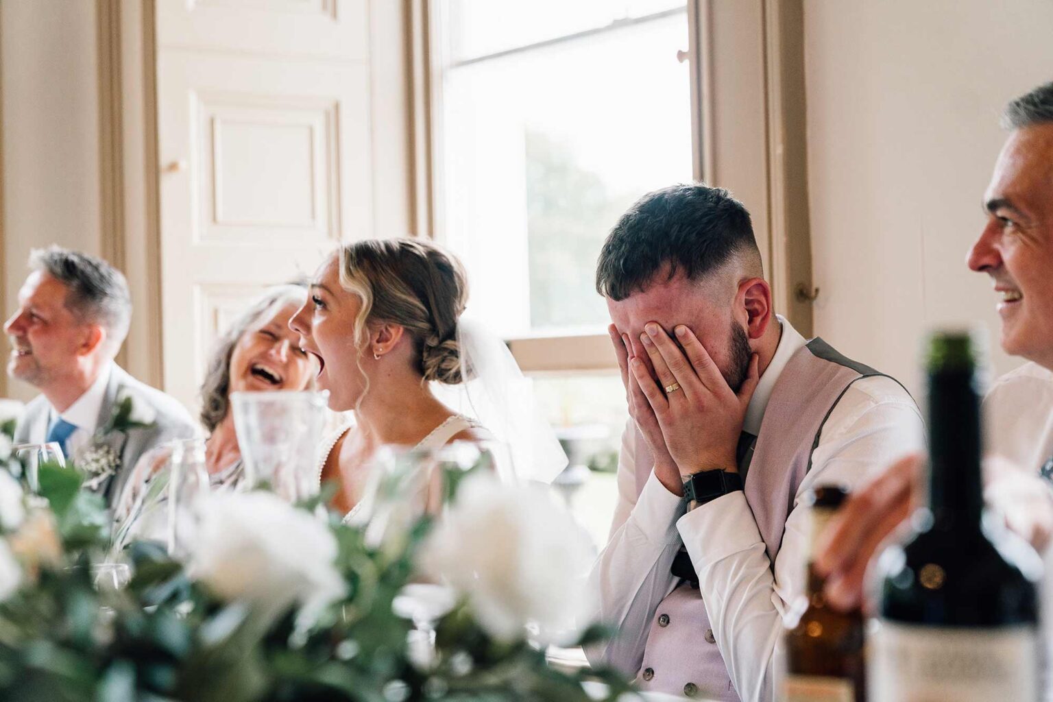 Brides shock reaction to grooms story during best man speech, groom has his hands in face out of disbelief, wedding is at crowcombe court, somerset.