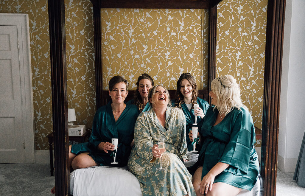 bridal party laughing on bed at holbrook manor
