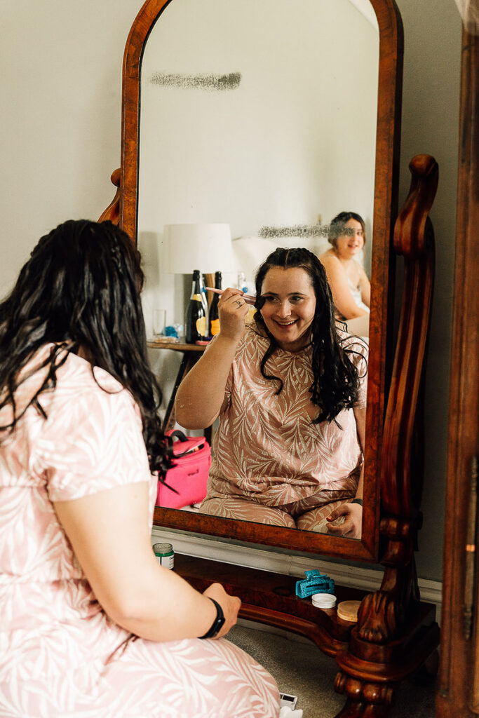 Bridesmaid looking in a mirror while doing her makeup