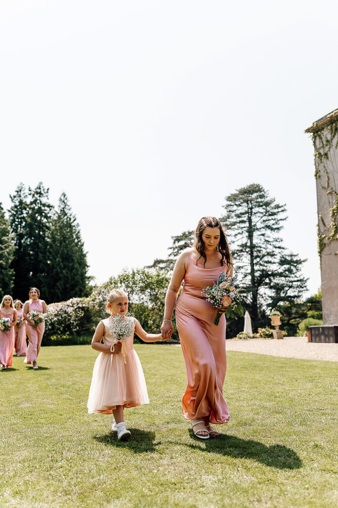 Bridesmaid walking with flower girl in the garden of pennard house