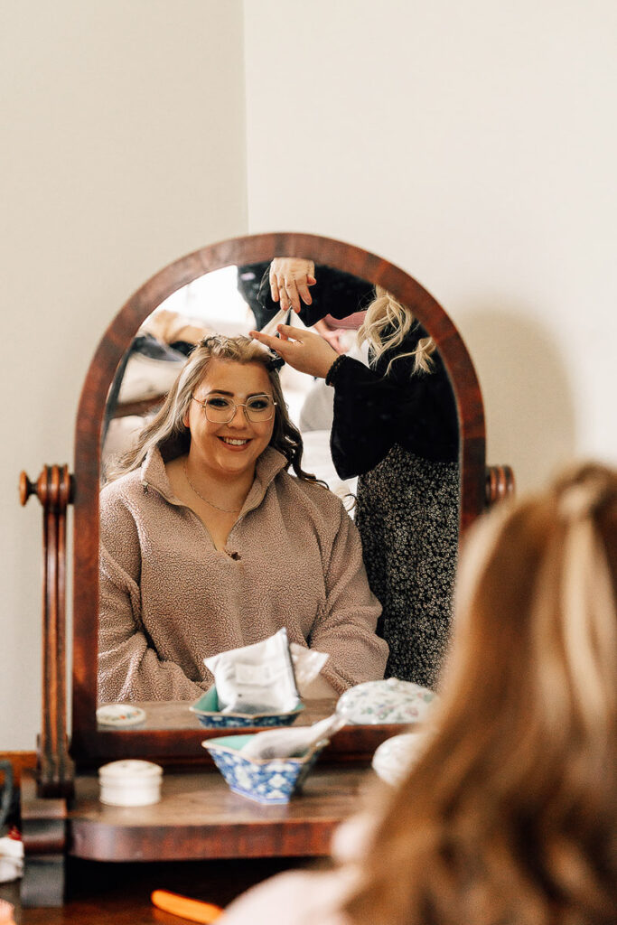 Bridesmaid looking in a mirror while having her hair prep done